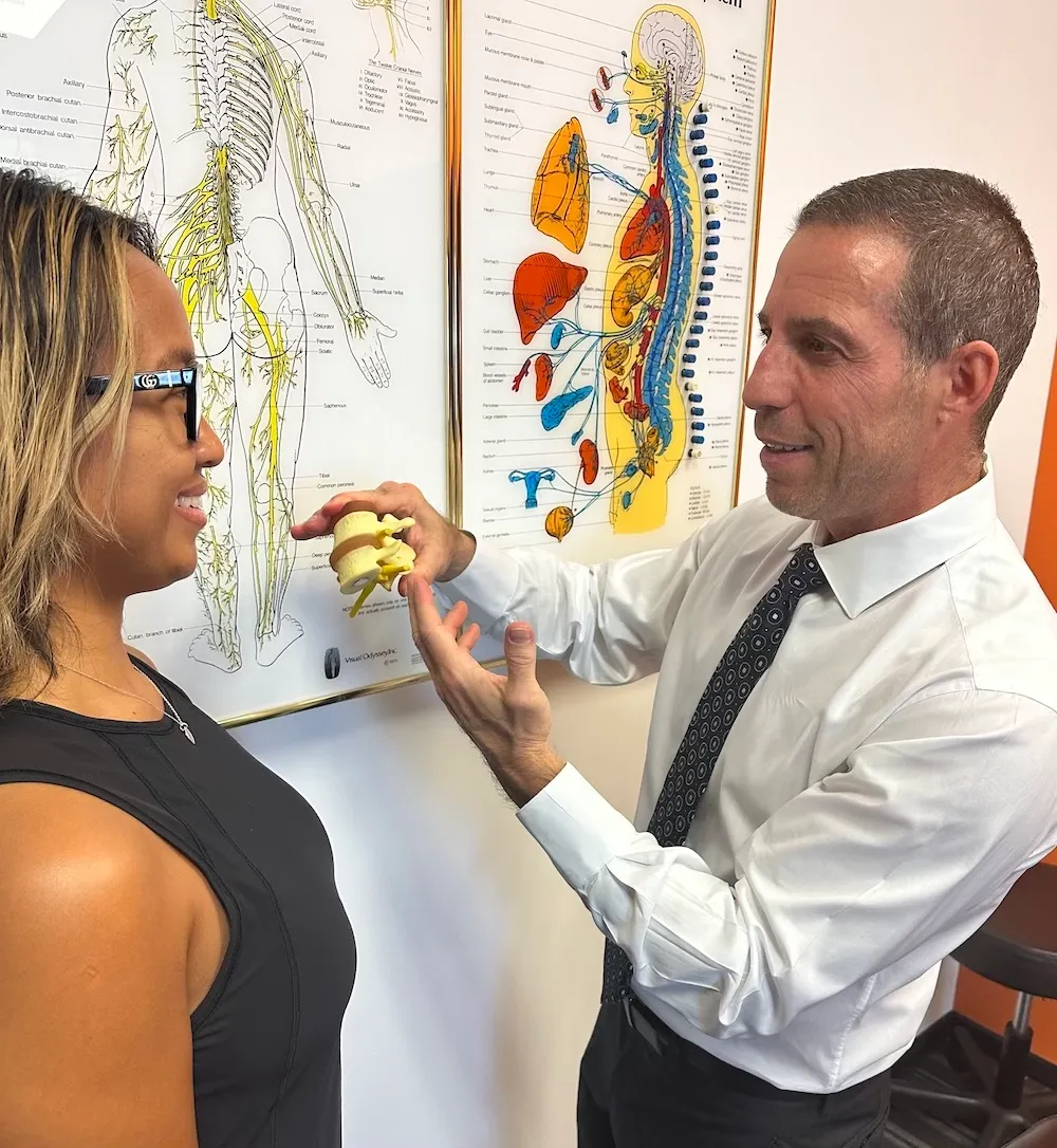 Dr. Ryan Alter showing a patient a model of the spine in Delray Beach