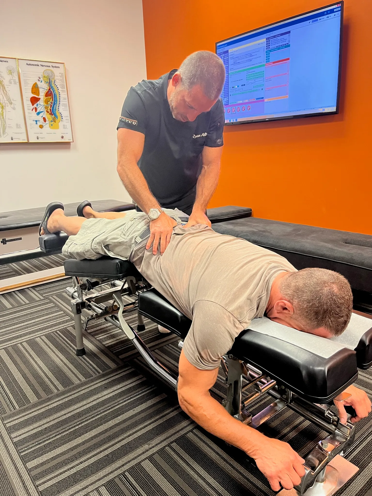 Chiropractor treating a patient lying face down on an adjusting table