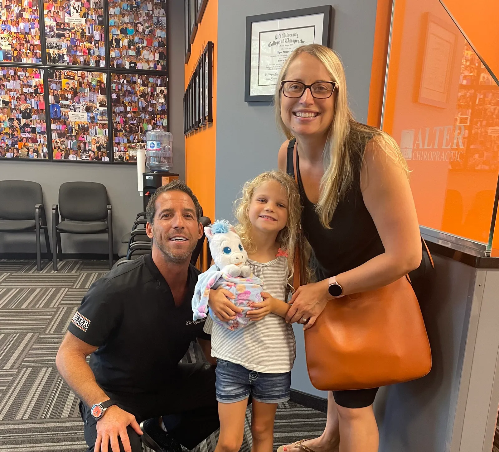 Dr. Ryan Alter with a young girl and her mother in the clinic