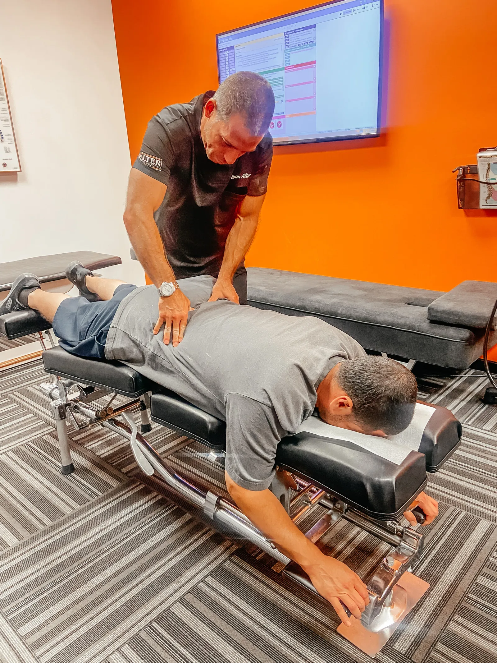 chiropractor adjusting a patient lying face down on a treatment table