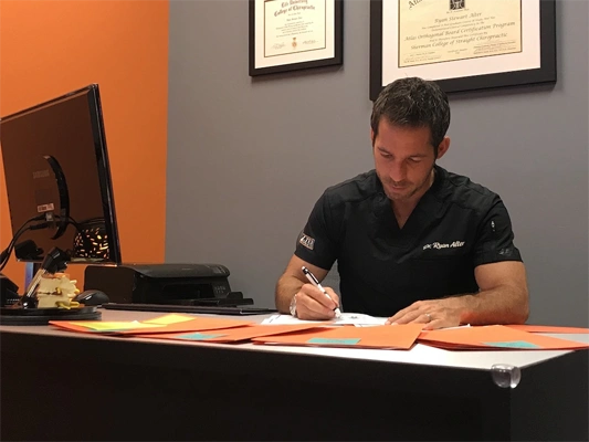 Chiropractor Delray Beach FL Ryan Alter At Desk First Visit